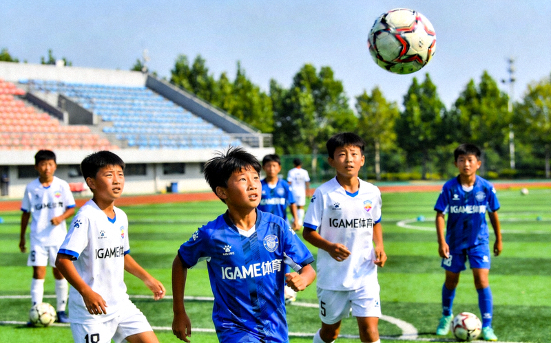 爱游戏IGAME体育新闻配图，青少年在操场上进行足球传接球练习