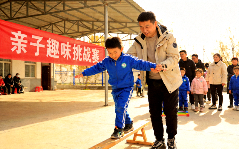 周末亲子趣味挑战赛现场，孩子在家长陪伴下完成平衡木挑战