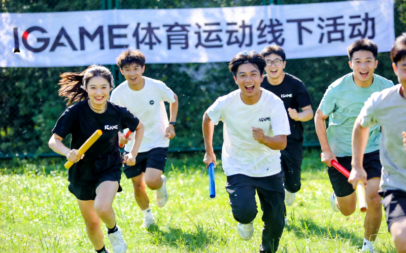 IGAME体育运动线下活动现场，年轻人在户外草坪上进行趣味接力比赛