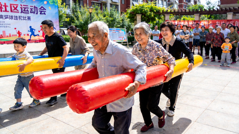 社区运动会上参与者进行趣味接力比赛，团队协作与欢笑并存，体现趣味运动带来的社区活力